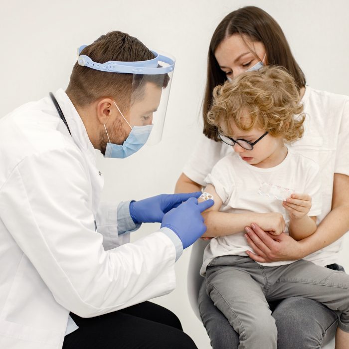 male doctor stick bandaid boy after vaccination